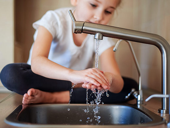 Water Scene Investigation Program. Girl washing hands on kitchen sink.