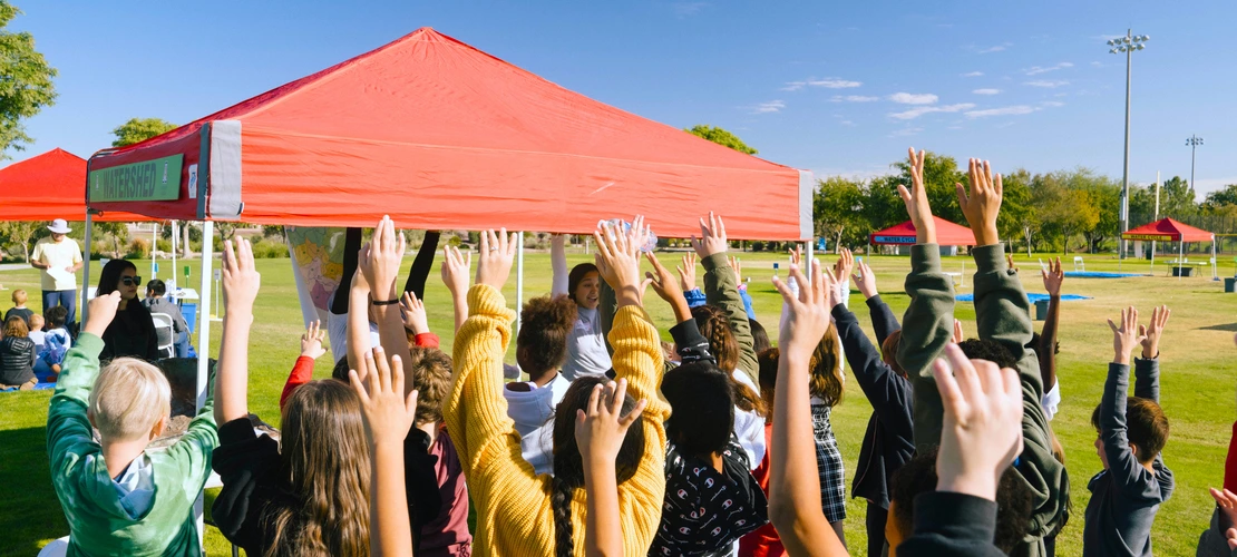 Student hands up in the air in a field
