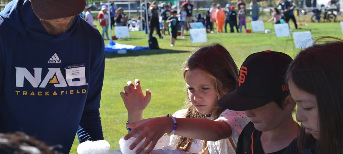 Volunteer and students playing with snow on a watershed model
