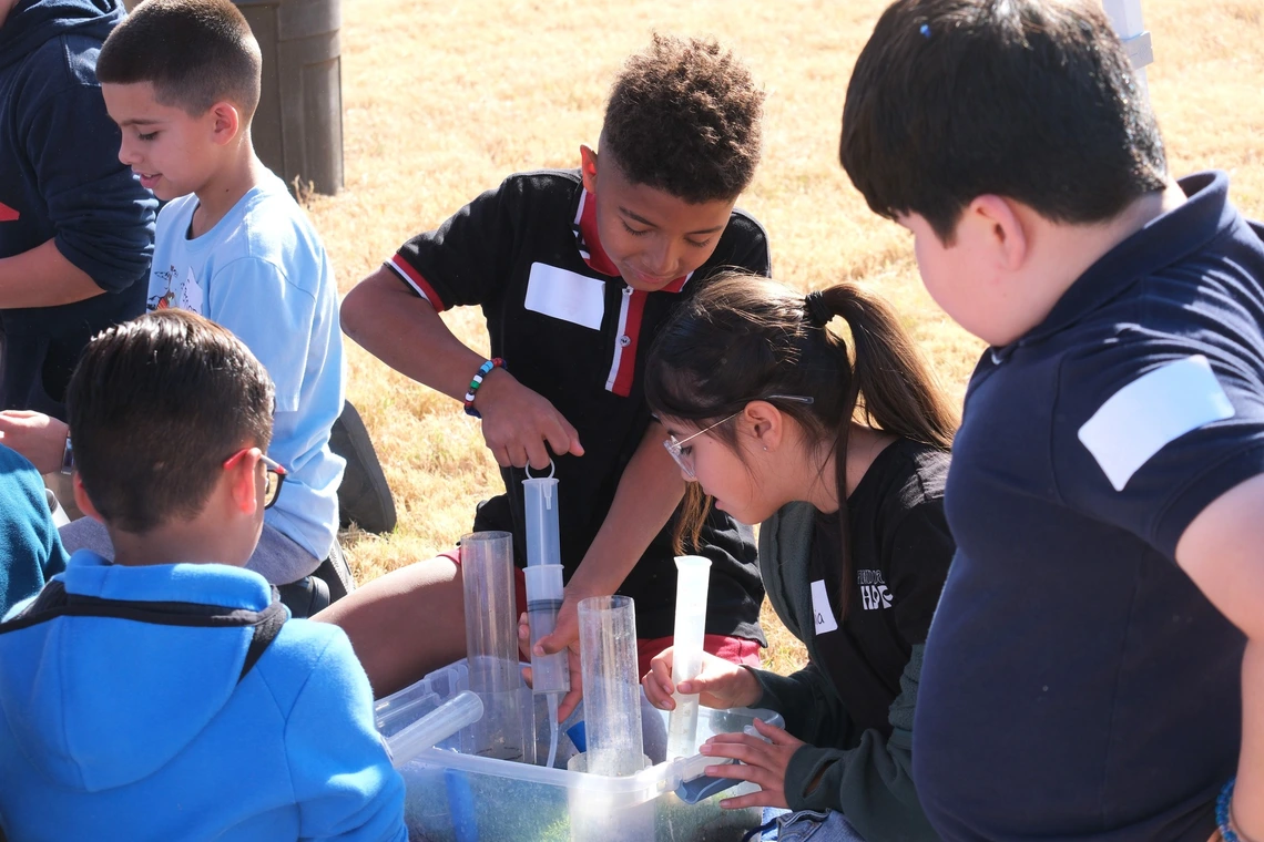 Students pumping groundwater out of an aquifer model at a water festival