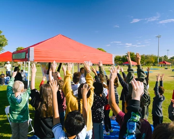 Student hands up in the air in a field